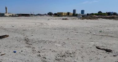 Gündüz vakti kumda plastik atıklarla ve molozlarla kaplı kirli bir sahilin havadan görüntüsü.