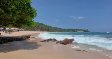 Sessiz Sahil Sri Lanka. Güçlü dalgalar ve açık gökyüzü altında sabah güneşi. Çok az insan görülebilir.