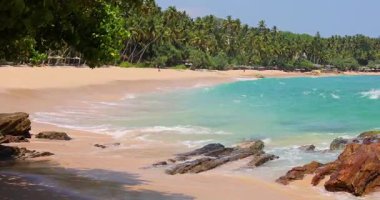 Sessiz Sahil Sri Lanka. Güçlü dalgalar ve açık gökyüzü altında sabah güneşi. Çok az insan görülebilir.