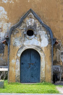 Yıpranmış mavi ahşap bir kapı kemerli bir çerçeveyle tarihi bir duvarda gün ışığında hiç insan olmadan.