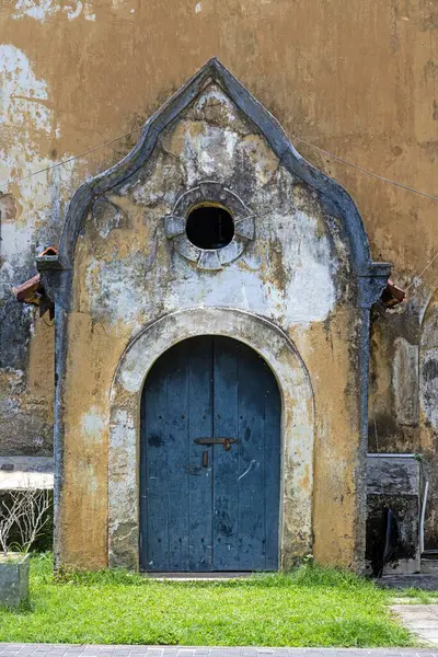Yıpranmış mavi ahşap bir kapı kemerli bir çerçeveyle tarihi bir duvarda gün ışığında hiç insan olmadan.