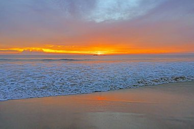 Ventura sahilinde güneş batıyor. Akşamları yumuşak dalgalar ve turuncu ışıltıyla.