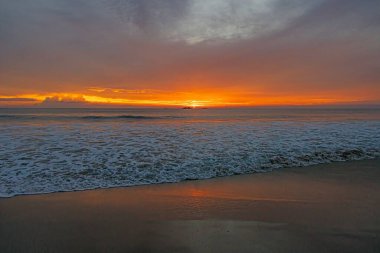 Ventura sahilinde güneş batıyor. Akşamları yumuşak dalgalar ve turuncu ışıltıyla.