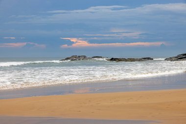 Geniş kumlu sahil manzarası mavi gökyüzü ve yazları tropikal kıyı şeridi.