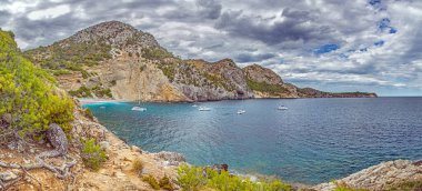Cala San Vincenc Körfezi 'nin kayalıkların ve turkuaz suların yanında demirli yatları var.