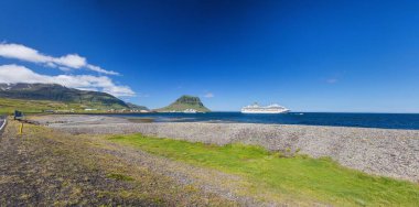 Iconic Kirkjufell dağı açık gökyüzünün altında mavi denizde seyir gemisi ile