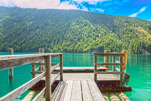 Zümrüt renkli Weissensee Gölü 'ne giden taşralı ahşap iskele.