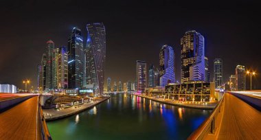 Dubai Marina Kanal boyunca yanan kuleler ve yansımalarla geceleri gökyüzü.