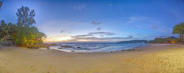 Gün batımında kayalık sahil ve sakin denizle Kata Beach Phuket 'in geniş panoramik manzarası