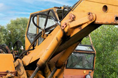 Old, dilapidated and rusty excavator with broken windows.