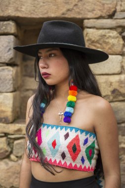 Genç And kızı Cusco Peru 'da Ollantaytambo' da poz veriyor. Peru 'dan halk kıyafetleri giyen genç bir latin manken. Cusco 'daki İnka döneminden geleneksel mimari.