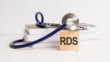 text RDS is written on wooden cube near a stethoscope on a white background clipart