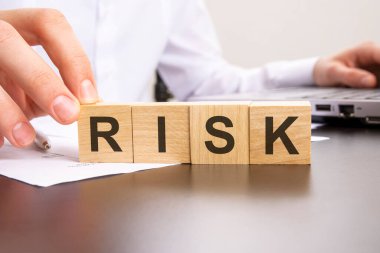 RISK, dizüstü bilgisayarda çalışan arka plandaki adamın tahta bloklarıyla yapılmış. seçici odak.