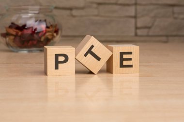 PTE - ahşap bloklardan harflerle kısaltma, İngilizce konsept yabancı dil sınavları Pearson Testleri, gri arka planda üst görünüm