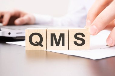 Masa arkasında QMS metni olan tahta bloklar. finansal, pazarlama ve iş kavramları