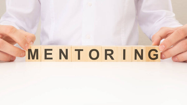MENTORING word made with building cubes, business concept.