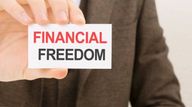 FINANCIAL FREEDOM yazılı bir kart tutan işadamı.
