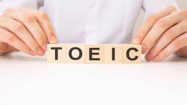 Eller ahşap küpü ve kelime TOEIC 'i çevirir, beyaz arkaplan