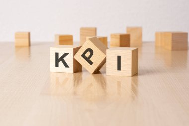kpi - Gri arka planda harfleri olan ahşap blokların kısaltması. Tablonun aynalı yüzeyindeki yansıma başlığı.