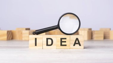 Üzerinde IDEA yazan büyüteç ve tahta bloklar. iş, pazarlama ve eğitim konsepti için kullanılabilir