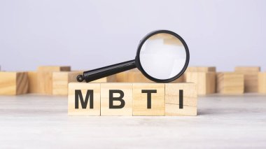 magnifying glass and wooden blocks with the text: MBTI. can be used for business, marketing and education concept clipart