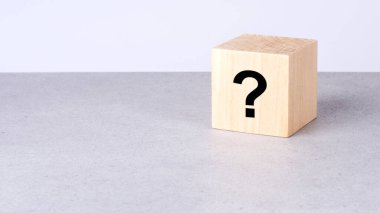 Beyaz zemin üzerinde soru işareti olan doğal tahta küp.