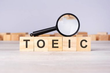 Tahta bloklar ve büyüteç metni: TOEIC - Uluslararası İletişim İçin İngilizce Testi