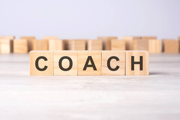 Слово COACH высечено на деревянных кубиках, лежащих на светлом столе. бизнес концепция.