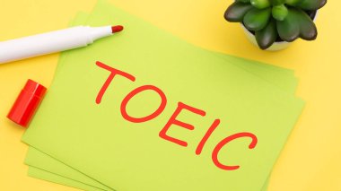 Kırmızı işaretli sarı arkaplanda TOEIC yazılı yeşil kart