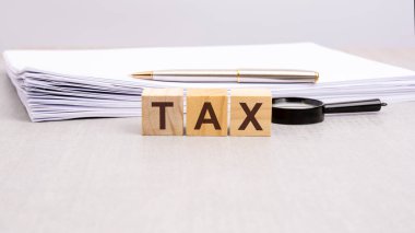 Tahta küplere siyah harflerle TAX yazılıydı. Küpler beyaz bir yüzey üzerindeydi..