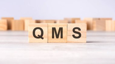 QMS - kısaltma kavramı açık gri arkaplanda tahta küplere veya bloklara yazılmıştır