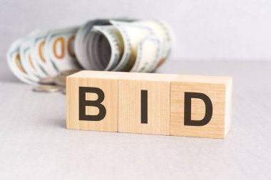 Tablonun gri yüzeyinde tahtadan bloklar ve arka planda dolar banknotları var.