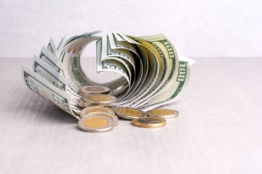 Bükülmüş dolarların ve bozuk paraların faturaları gri bir masanın üzerinde, yakın plan, ön manzara.