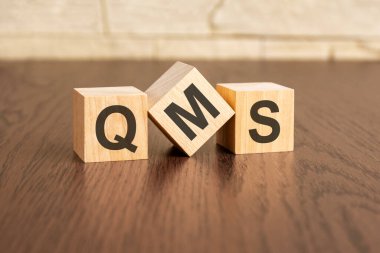 Tahta küplerde TQM sembolleri olan toplam kalite yönetim kavramı, koyu ahşap arkaplan