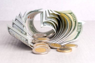 Bükülmüş dolarların ve bozuk paraların faturaları gri bir masanın üzerinde, yakın plan, ön manzara.
