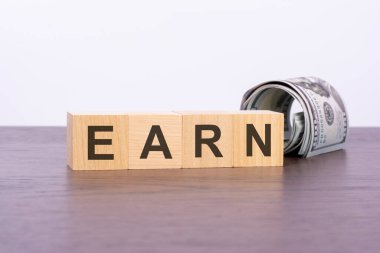 Tahta bloklar hakkında EARN ve karanlık arka planda banknotlar, iş ve finans kavramı