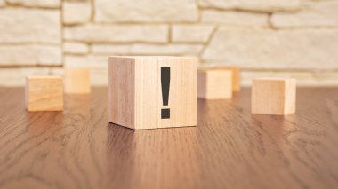 Masada ünlem işaretli tahta küpler, koyu ahşap arka plan.