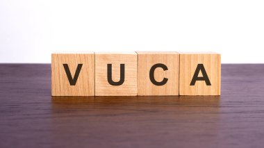 Tahta küplerle VUCA yazıyor. Tahta elementlerin harflerle toplandığı kavramsal bir kelime. stok resmi, kahverengi arkaplan
