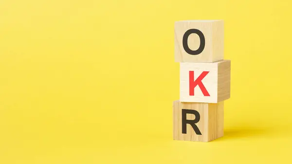 wooden cubes with text OKR. yellow background