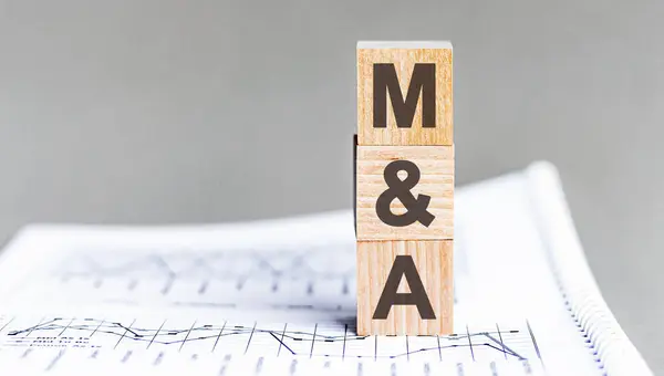 word M and A - Mergers and Acquisitions - acronym concept on cubes and diagrams on a gray background. business as usual concept image.