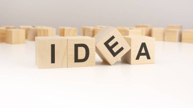 Bir masanın üzerinde duran tahta zarlara yazılmış IDEA metni, gri arkaplan