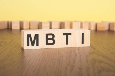 Kısa kelime İngilizce harfleri, küçük tahta bloklar üzerinde MBTI yazılı. kahverengi arka plan. seçim odağı.
