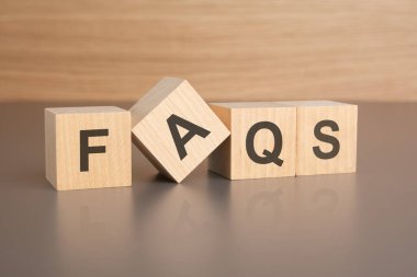 Kahverengi bir masanın parlak yüzeyinde FAQS harfleri olan dört tahta küp. Küplerdeki yazıtlar masanın yüzeyinden yansıyor. iş kavramı.