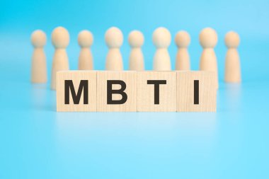 the term MBTI is inscribed on wooden blocks on a bright blue background. the image has selective focus on four blocks. wooden figures of people in the background. clipart