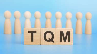Mavi arka planda tahta küplerle ilgili TQM metni. toplam kalite yönetim kavramı
