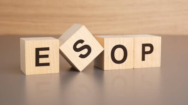 Kahverengi bir masanın parlak yüzeyinde ESOP harfleri olan dört tahta küp. Küplerdeki yazıtlar masanın yüzeyinden yansıyor. iş kavramı.