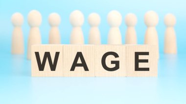 Ücret terimi parlak mavi arka planda tahta bloklara yazılır. Görüntü dört blok üzerine odaklanmış durumda. Arkaplanda tahtadan figürler var..