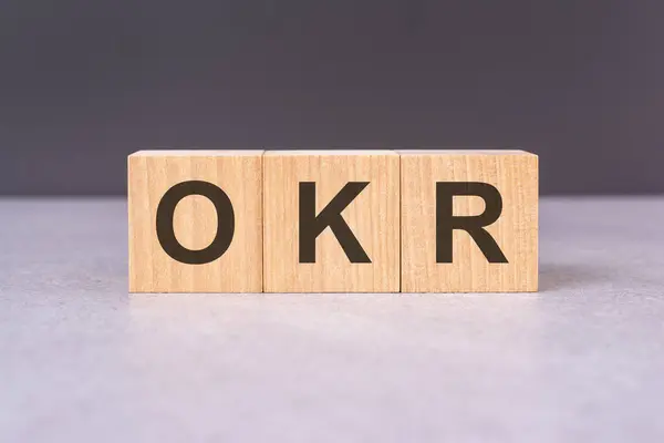 OKR - acronym from wooden blocks with letters, top view on black background