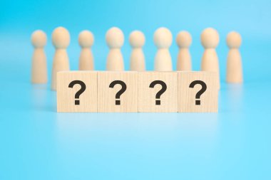 dört soru işareti parlak mavi bir arka planda tahta bloklara kazınmıştır. Görüntü dört blok üzerine odaklanmış durumda. Arkaplanda tahtadan figürler var..