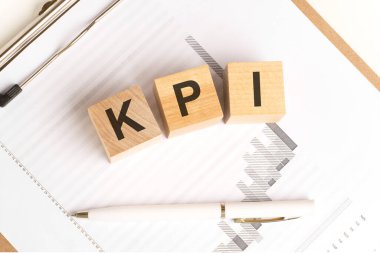 KPI sözcüğünün yer aldığı tahtadan küplerin finansal altyapısı tablo ve kalemle, iş konsepti